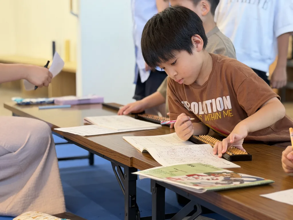 教室でそろばんの練習をする子どもたち